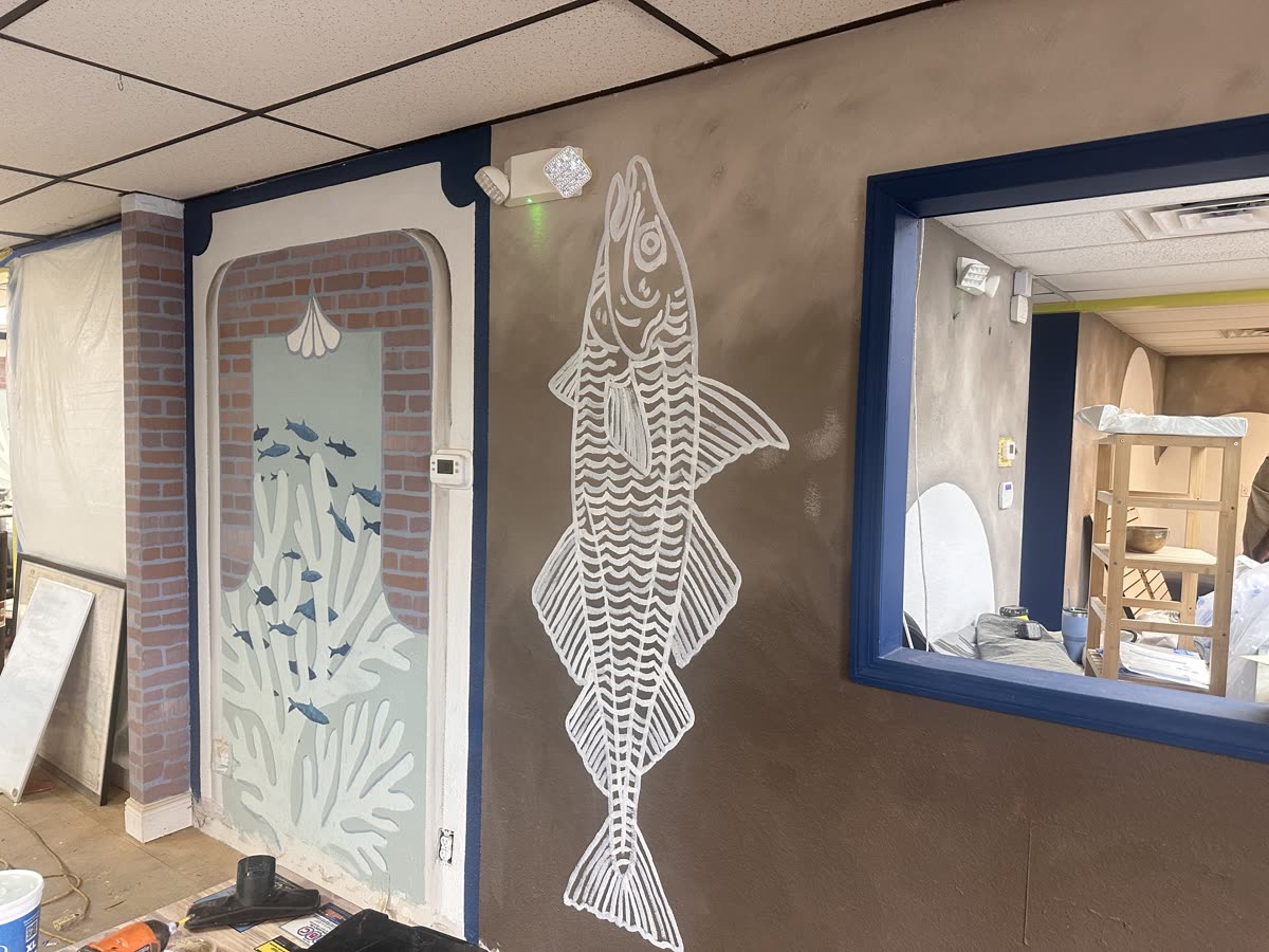 The entry taking shape — fish and shell murals around the doorway and pass-through window